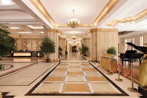 Eine prachtvolle Hotelhalle mit einer langen Rezeption, einem Flügel und einer Kristallleuchter.