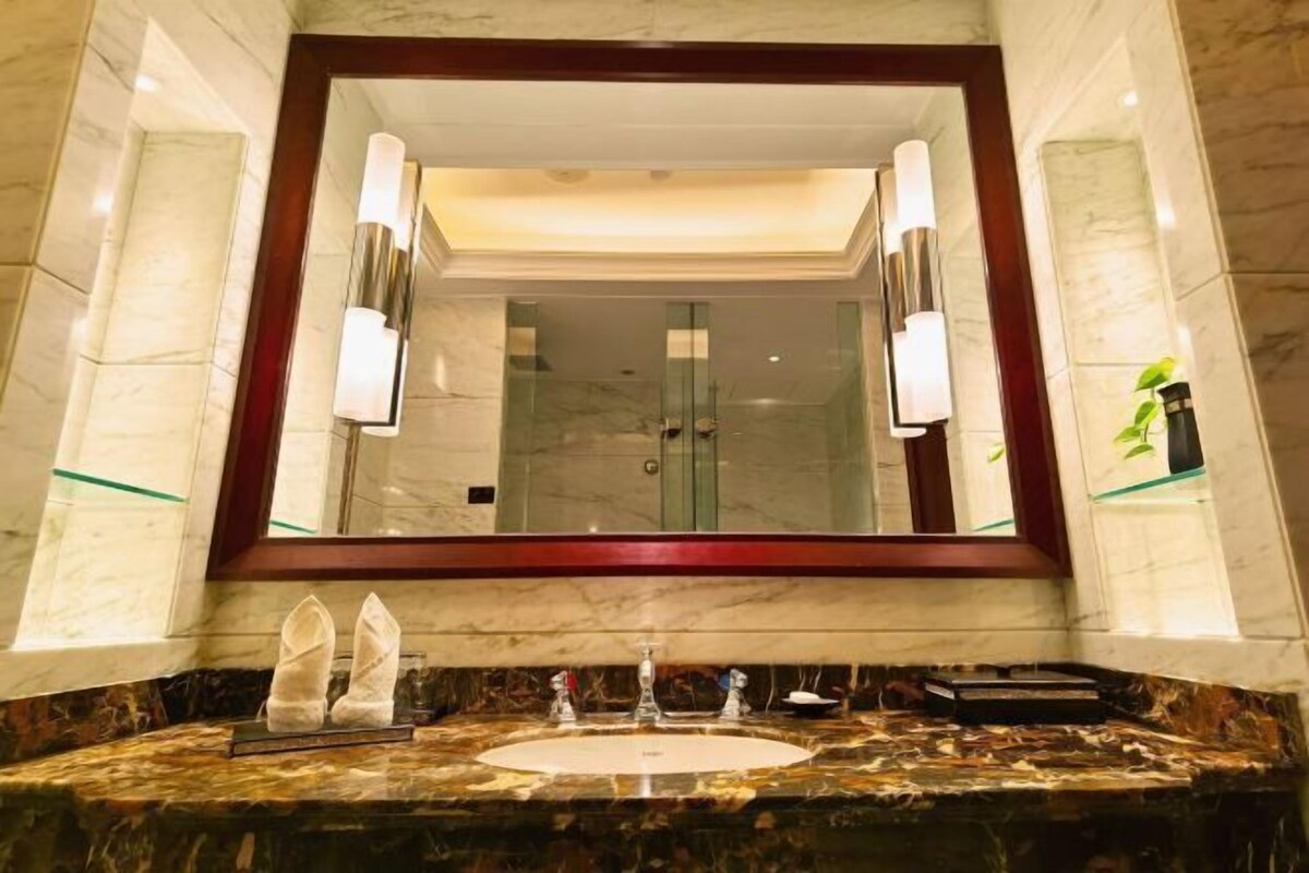 A bathroom with a marble vanity, a large mirror, and a glass shower enclosure.