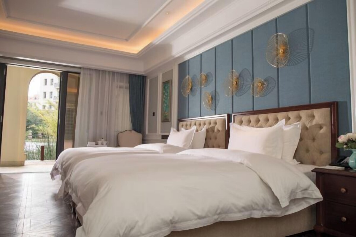 A hotel room with two beds, a large window, and decorative wall art.