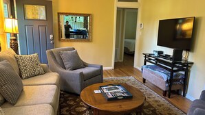 A living room with a sofa, armchair, coffee table, and a TV on a stand.