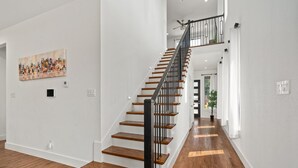 Ein modernes Interieur mit einer Holztreppe, weißen Wänden und einem Stadtbildgemälde.