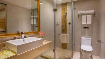 A modern bathroom with a glass-enclosed shower, a large mirror, a white sink, and a toilet.