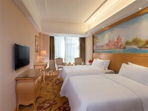 A hotel room with two beds, a TV, a desk, and a painting of a cityscape. - Vienna Classic Hotel Shenzhen Baoneng City Plaza (Shenzhen)