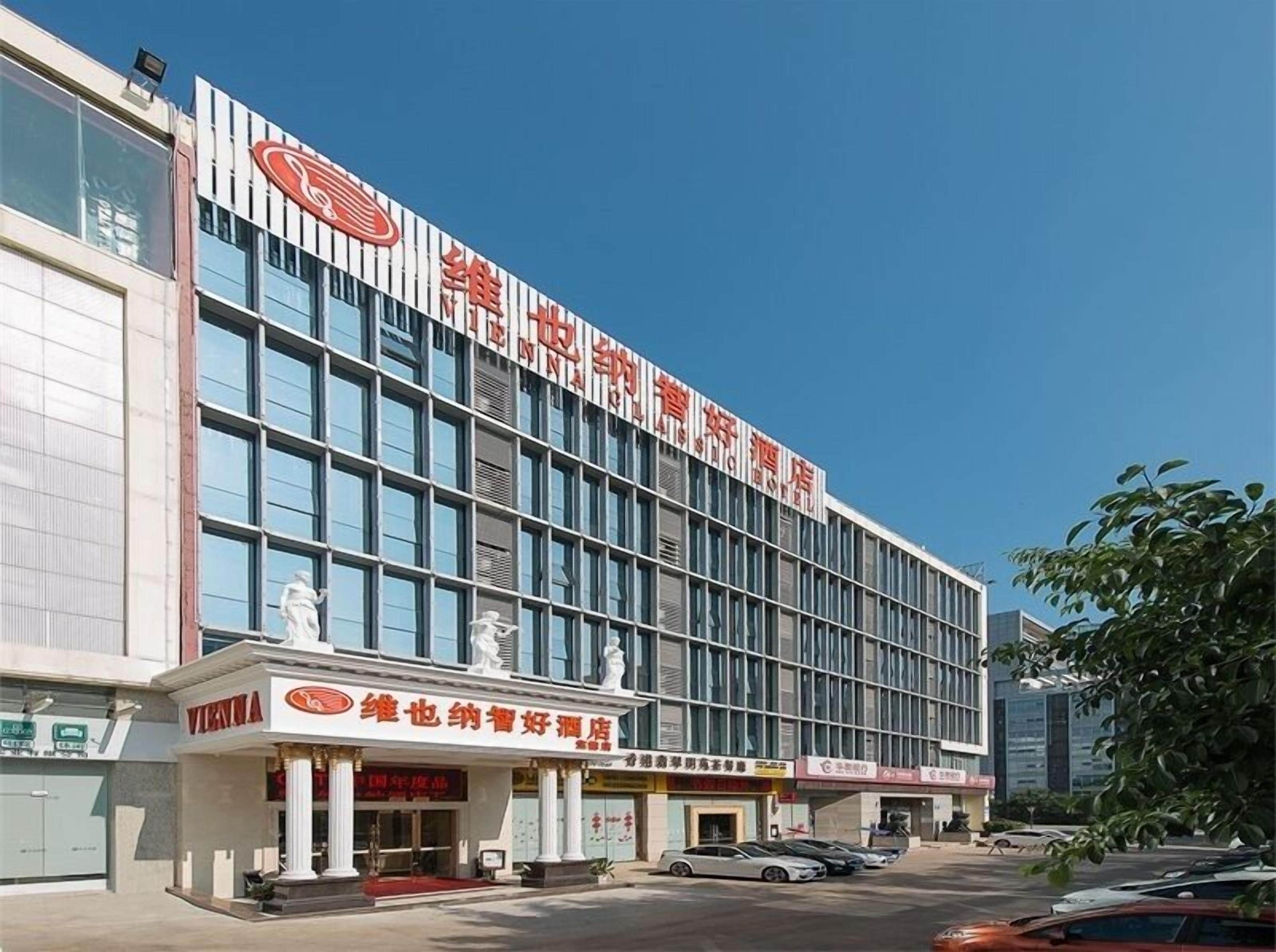 Een modern hotelgebouw met een opvallend bord, grote ramen en een standbeeld bij de ingang.