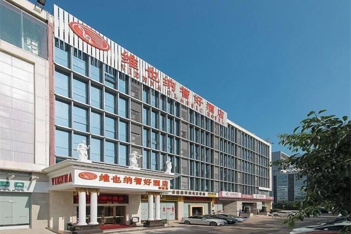 Un hôtel moderne, avec une enseigne bien visible, de grandes fenêtres et un espace de stationnement à l’avant.