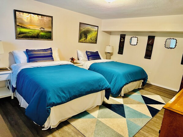 A hotel room with two beds, a desk, a lamp, and artwork on the walls. - Sweet one bedroom, 2 beds at the bakery (HAINES)
