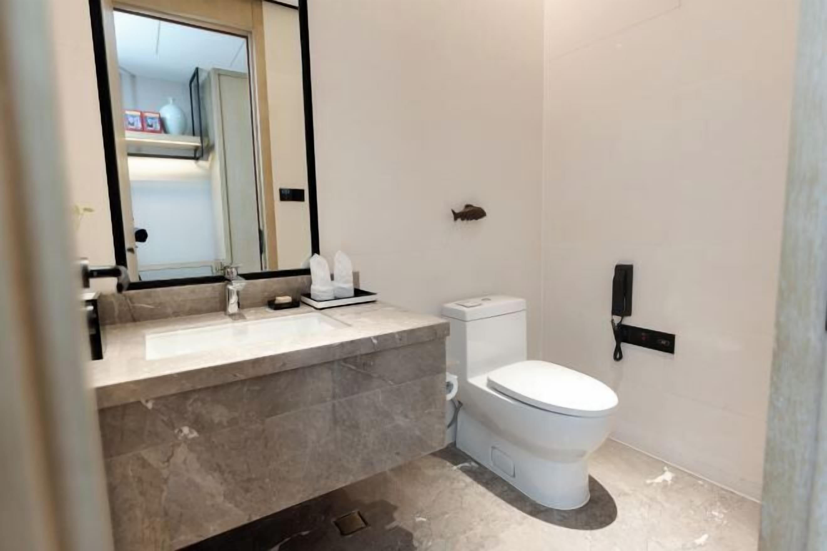 A modern bathroom with a marble sink, white toilet, and a fish decoration on the wall.