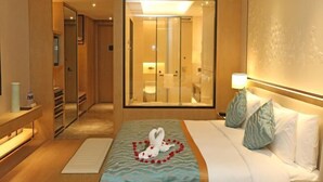 A hotel room with a bed, a bedside table, a mirror, and a view of the bathroom. - Xiangyi Hotel (Danyang)