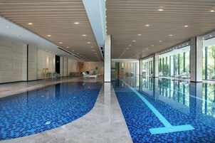 Uma grande piscina interna com piso em azulejo e design curvo.