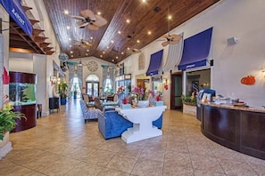 A spacious lobby with a high ceiling, wooden beams, and a reception desk.