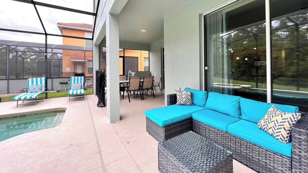 A covered outdoor patio area with a pool, seating, and a dining area.