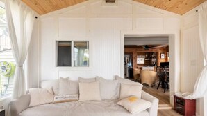 Un dormitorio con una cama grande, una ventana con cortinas y vista al comedor.