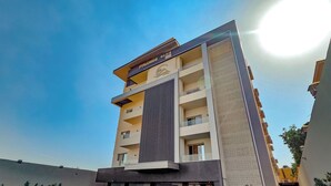 Un hôtel moderne qui se distingue par son design à rayures verticales bien marquées, ses nombreux balcons et son espace extérieur bien entretenu, agrémenté de plantes en pot.