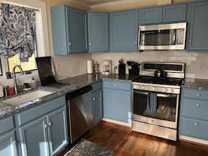 A kitchen with blue cabinets, a stainless steel stove, a microwave, and a dishwasher.