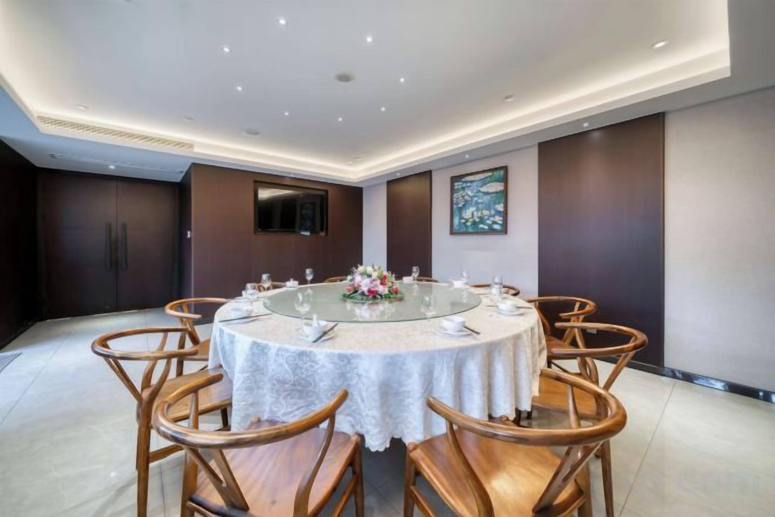 A conference room with a round table, chairs, and a floral centerpiece.