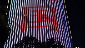 Fachada de edificio con tiras de luz verticales y un símbolo rojo.