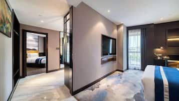 A modern hotel room with a large bed, a flat-screen TV, a desk with a chair, and a view of the city through the window.