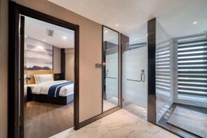 A modern hotel room with a bed, a glass shower enclosure, and a view of the mountains through the window. - BBH Hotel (Xinchang Ocean City) (Xinchang)