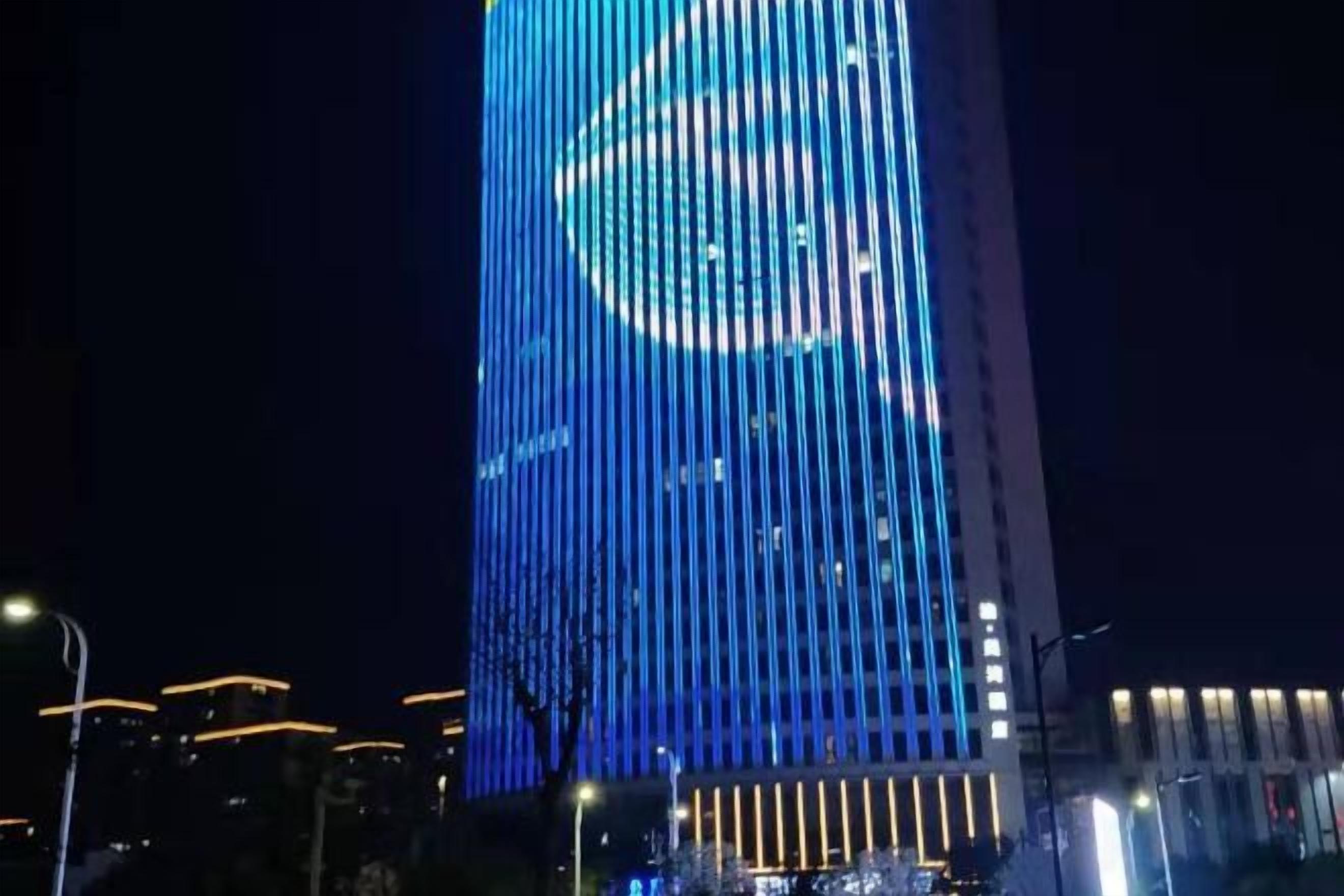 A tall building with vertical lines and a circular design at the top.