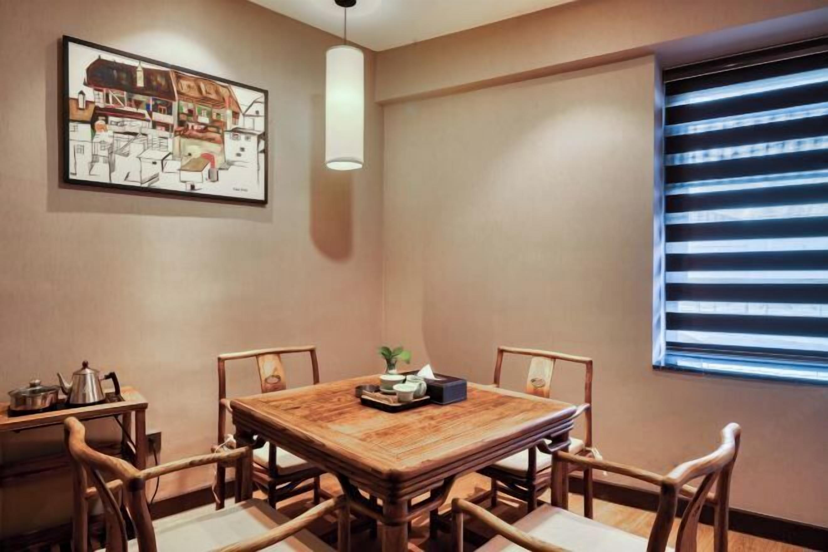 Un comedor con mesa y sillas de madera, un cuadro en la pared y una ventana con persianas.