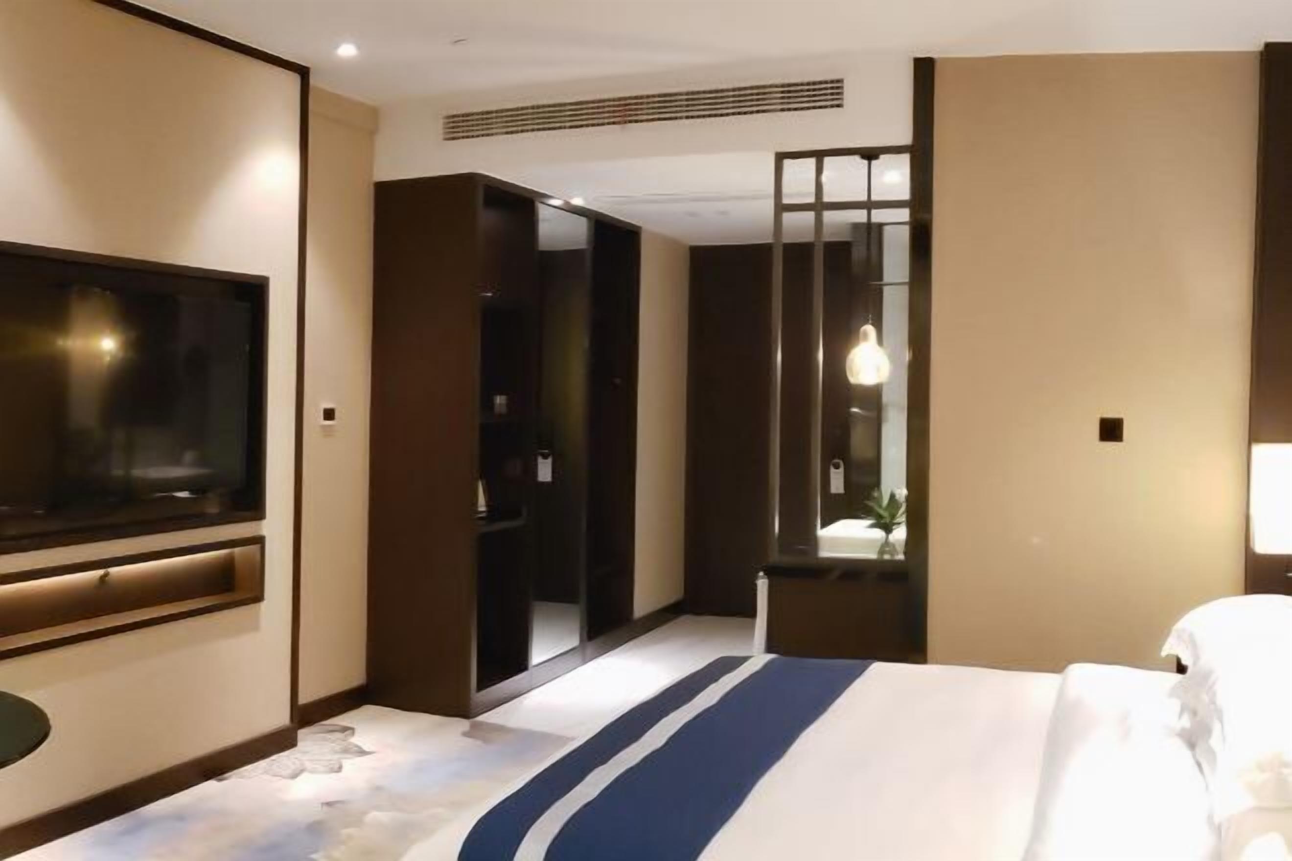 Una habitación de hotel con cama, televisión, armario y espejo.