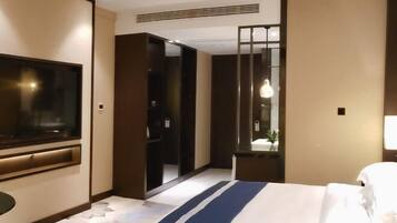 Una habitación de hotel con cama, televisión, armario y espejo.