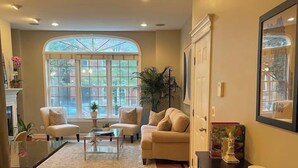 A spacious living room with a large window, a fireplace, and a dining area with a wooden floor. - Ukrainian Village 3BR/3BA • Private Patio, Parking (Chicago)