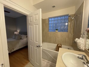 Een bad/douchecombinatie, een bubbelbad, een haardroger, handdoeken