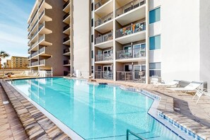 Relax by the pool surrounded by lounge chairs and umbrellas, with stunning views from the hotel's balconies.