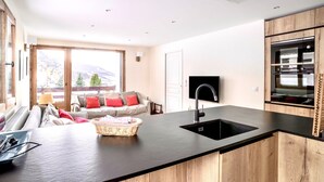 A modern kitchen with a black countertop, wooden cabinets, and a built-in oven. - Fantastic fully renovated flat in Megève (Megève)