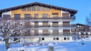 A multi-story hotel with balconies, wooden facade, and snow-covered surroundings. - Fantastic fully renovated flat in Megève (Megève)