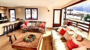 A modern living room with a sofa, a coffee table, and a view of a snowy landscape through large windows. - Fantastic fully renovated flat in Megève (Megève)