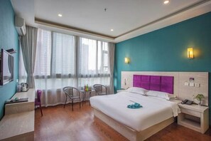 Una habitación de hotel con cama, mesita de noche, silla y escritorio con otra silla.