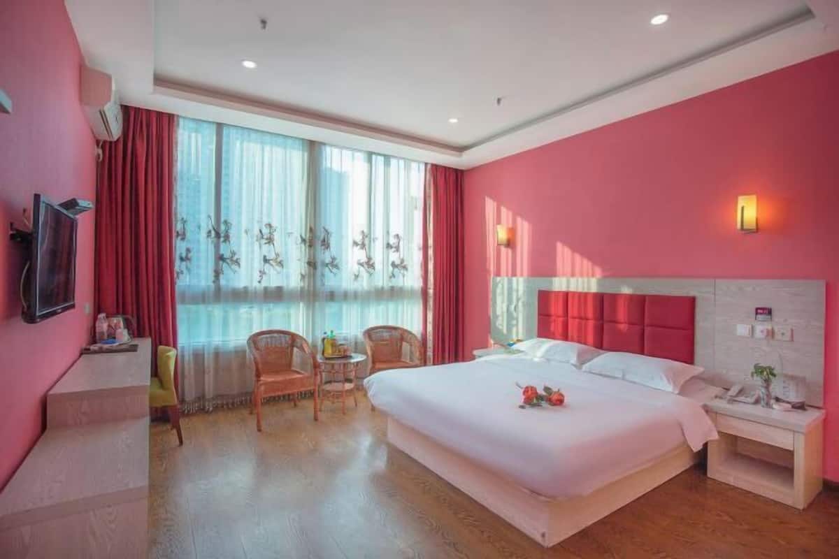 Ein Hotelzimmer mit einem großen Bett, einem Schreibtisch, einem Stuhl und einem kleinen Tisch.