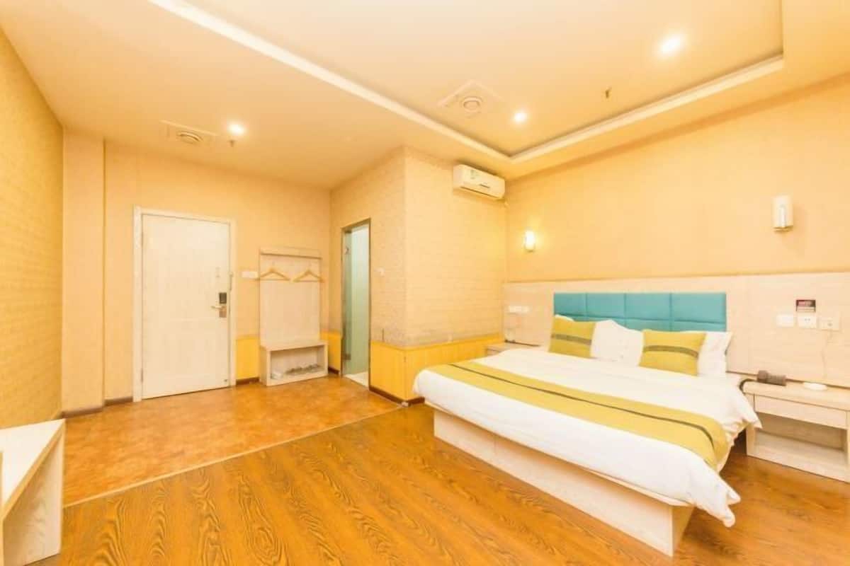 Ein Hotelzimmer mit einem großen Bett, einem Nachttisch, einem Kleiderschrank und einer Wand-Klimaanlage.