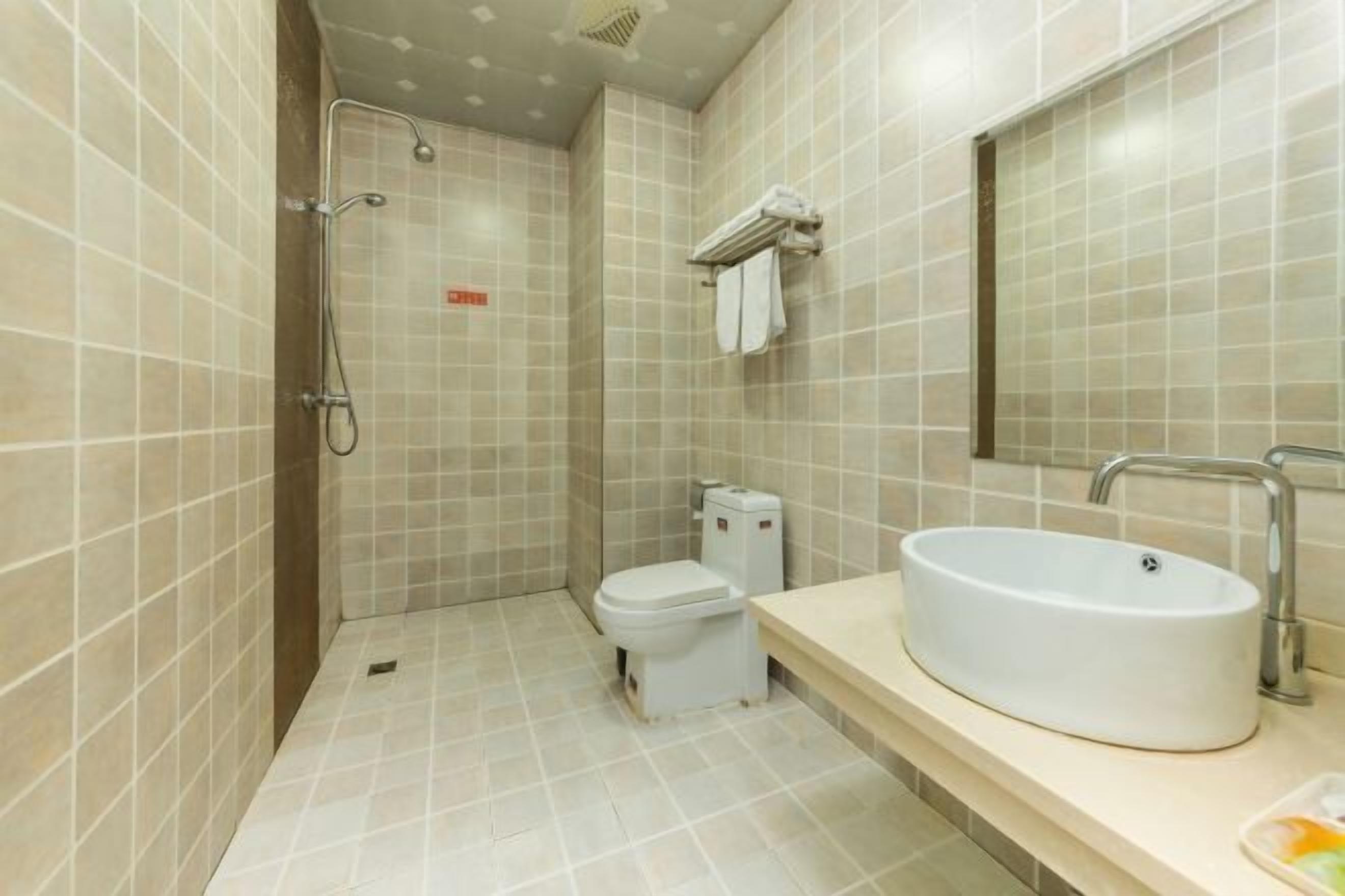 A bathroom with a shower, toilet, sink, and mirror.