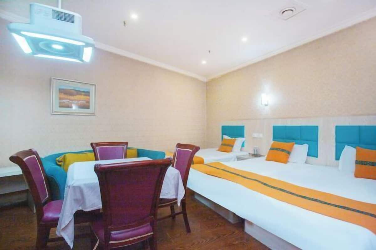 Ein Hotelzimmer mit einem Bett, einem Esstisch mit Stühlen und einer Deckenleuchte.