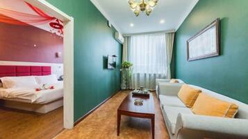 A hotel room with a bed, a sofa, a coffee table, and a chandelier.