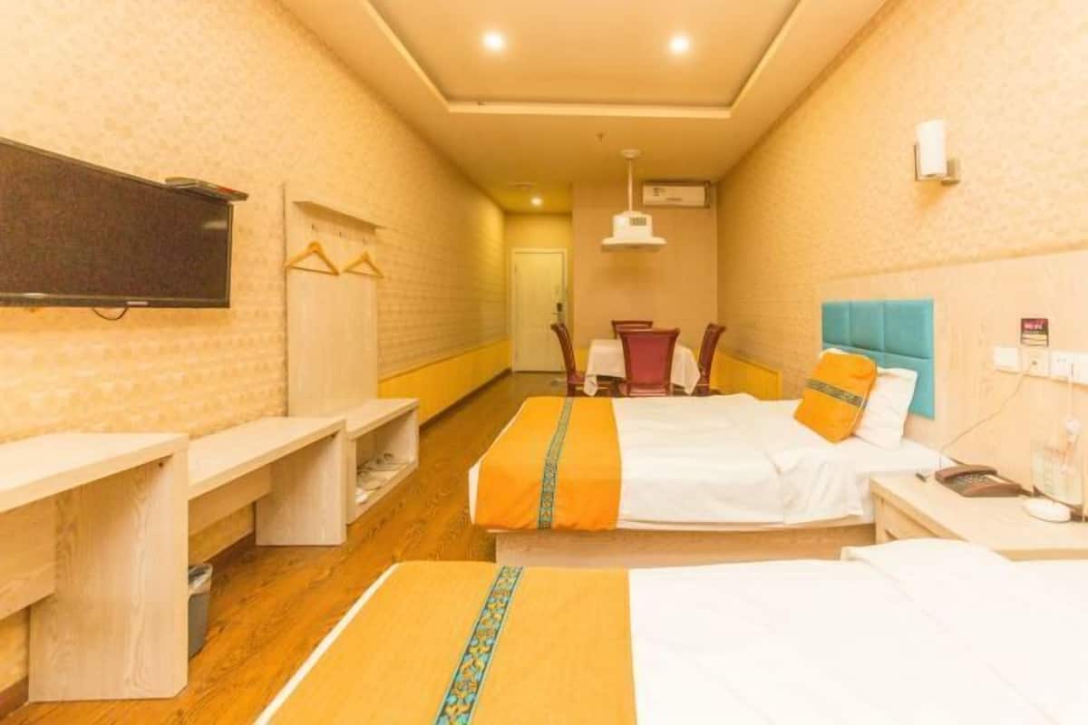 Ein Hotelzimmer mit zwei Betten, einem Schreibtisch, einem Stuhl, einem Fernseher und einem Kleiderschrank.