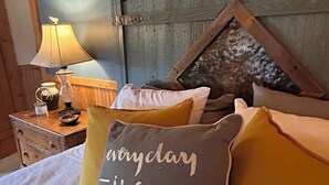Un lit avec plusieurs oreillers, une lampe et une tête de lit en bois.