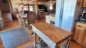 Une cuisine rustique avec des poutres en bois, une grande table en bois et un réfrigérateur.