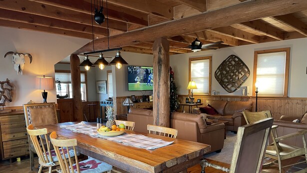 Un coin repas rustique avec une table en bois, des chaises et un panier de fruits.