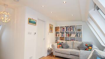 A modern living room with a grey sofa, a bookshelf, and a decorative light fixture.