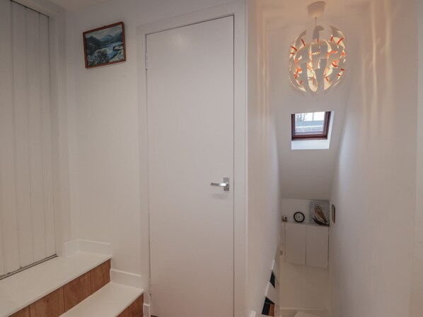 A hallway with a white door, a small window, a wall-mounted clock, and a decorative light fixture. - 3 Dunrobin Street (Tain)