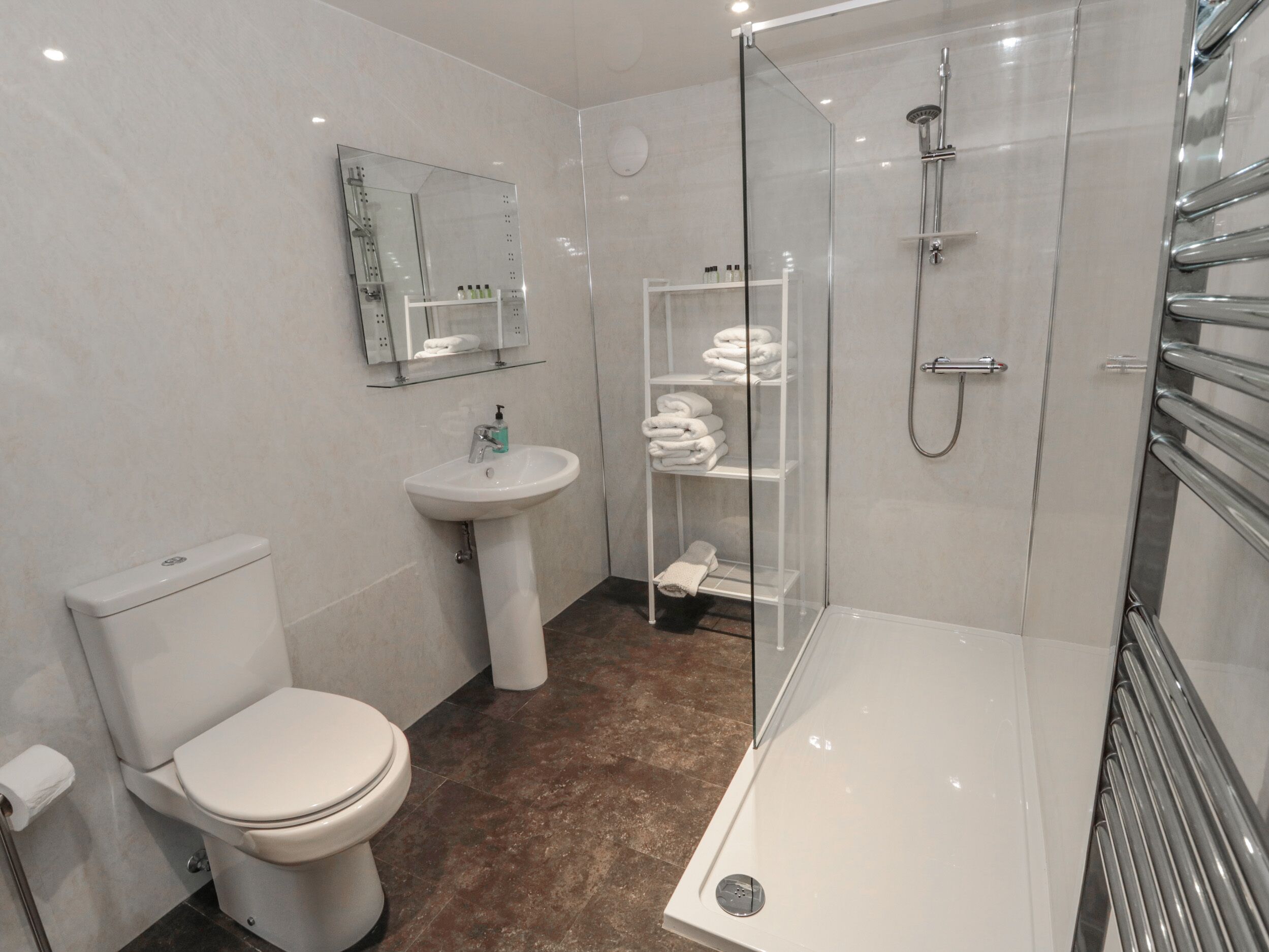 A modern bathroom with a toilet, sink, glass shower enclosure, and a glass-enclosed shower area.