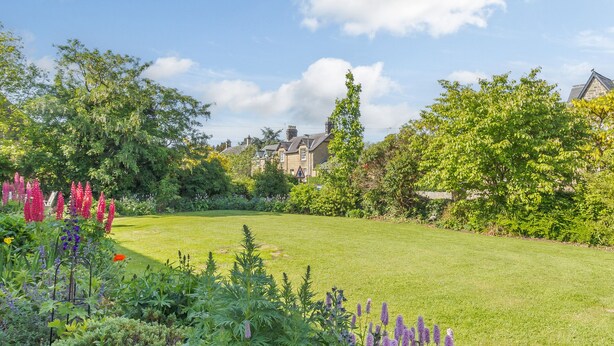 A well-maintained garden with a variety of flowering plants and a lawn. - Barnacre (Morpeth)