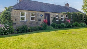 A stone building with a dark tiled roof, a black door, and a sign that reads "Barnacle". - Barnacre (Morpeth)