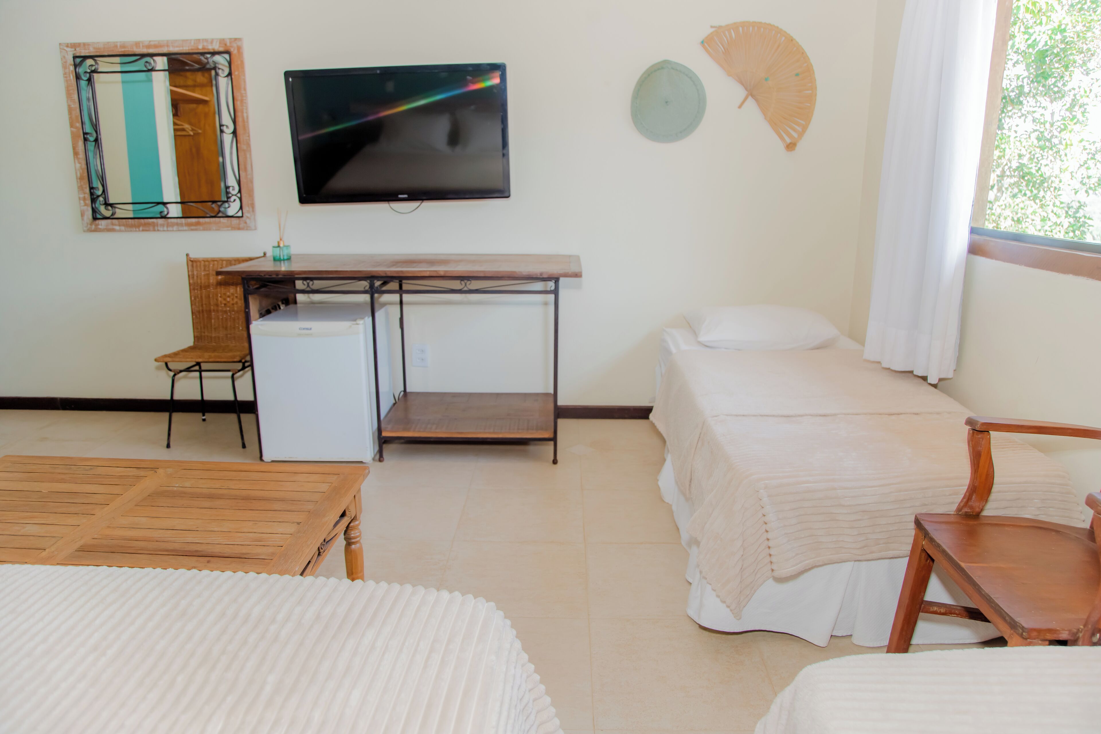 A hotel room with a bed, a desk with a computer, a TV, and a window with curtains.