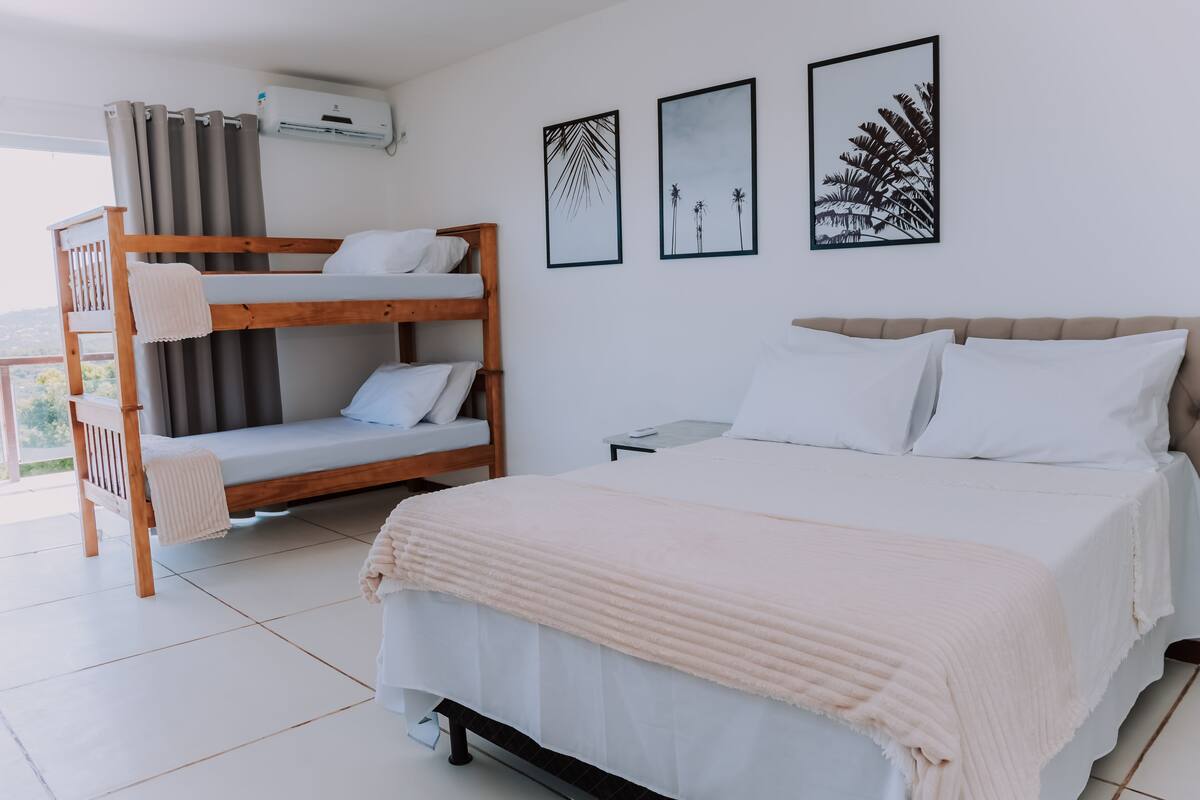 A bedroom with a bunk bed, a single bed, and two framed pictures on the wall.