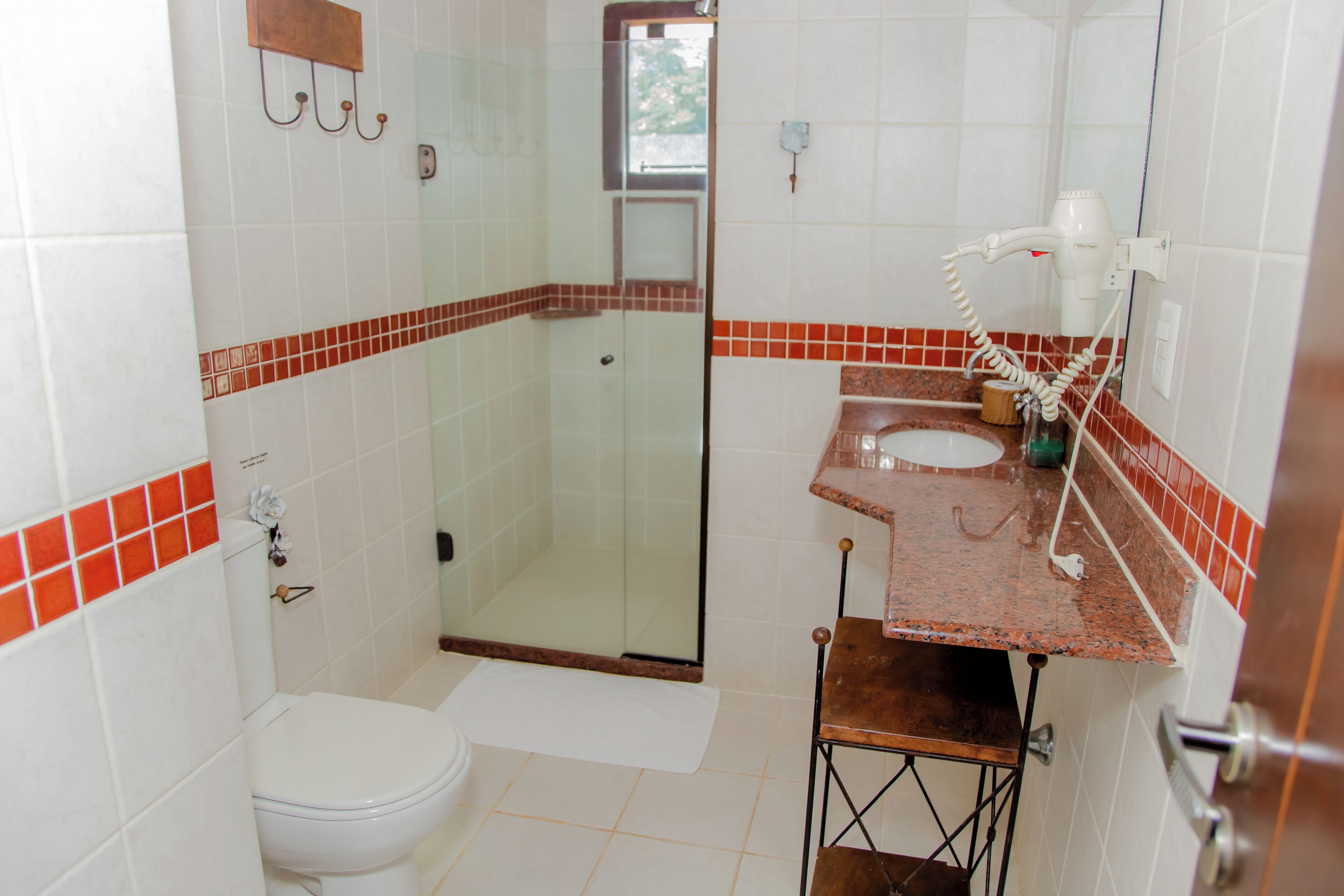 A bathroom with a toilet, a glass-enclosed shower, a sink with a mirror, and a towel rack.